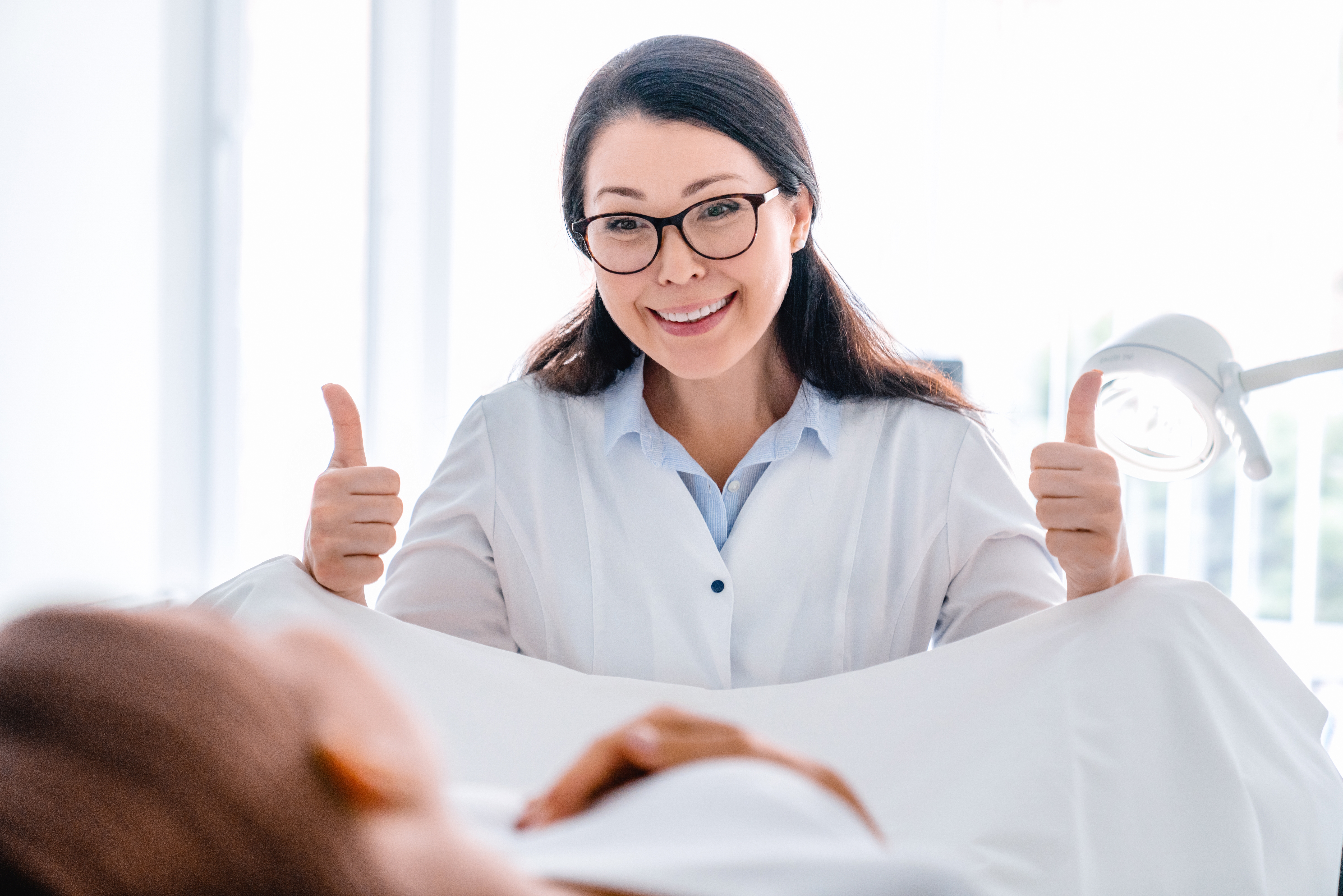 Smiling,Mid,Adult,Gynecologist,Examines,A,Woman,In,Modern,Clinic